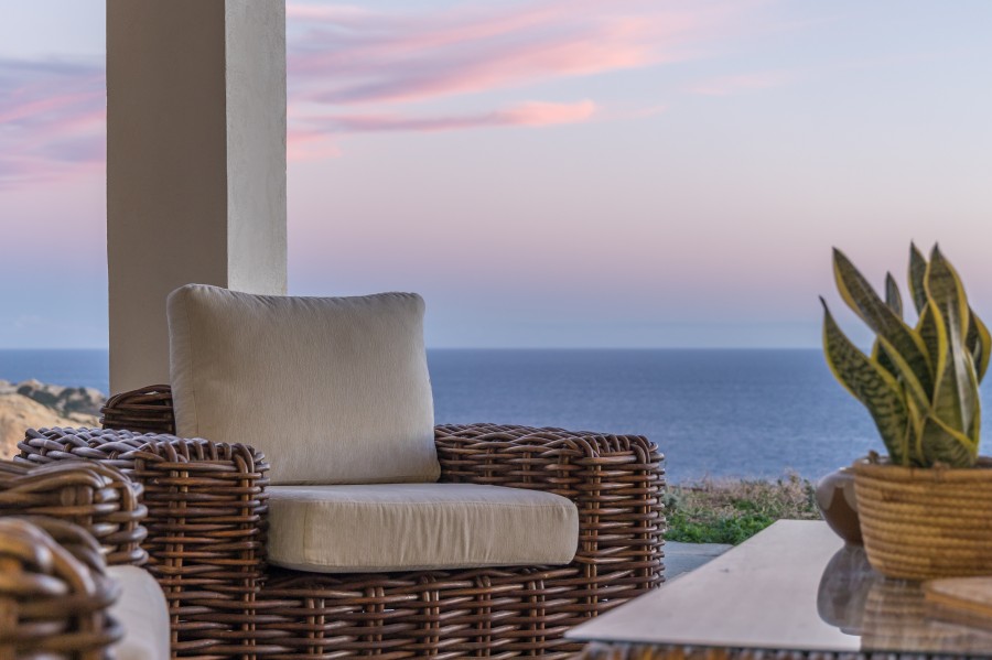 Romantic private dining experience on a Milos beach at sunset, featuring a set table with champagne, wine, and a single rose, ideal for special occasions.
