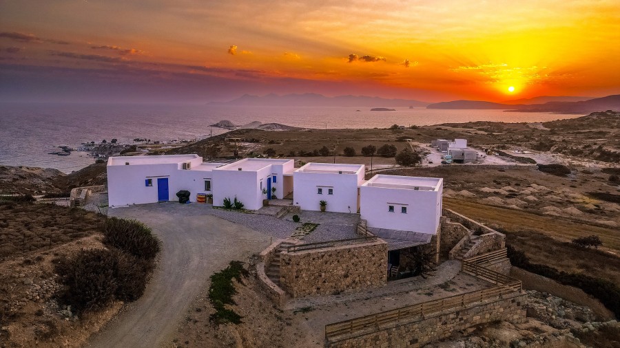Exclusive private dining setup with candles and a table for two, set on a scenic Milos hillside with a luxury SUV nearby, perfect for a romantic special event.